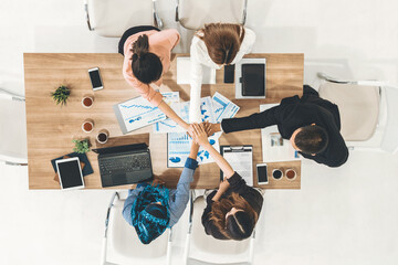 Businessmen and businesswomen joining hands in group meeting at multicultural office room showing teamwork, support and unity in business. Diversity workplace and corporate people working concept. uds