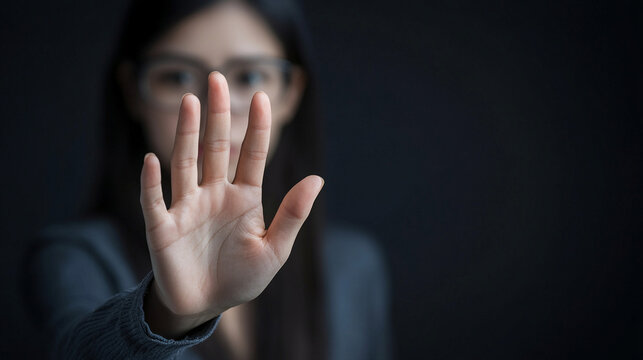 palm-out gesture, signaling 'stop,' stands out against a blurred background, conveying a clear message of halting or pausing