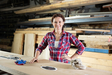 Female sawmill worker cleaning up excess resin or glue on a wooden board