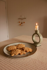 Merry Christmas! Gingerbread cookies lie in a plate on the table, there is a candle and lollipops. The background is a beautiful cozy home interior. Time for family
