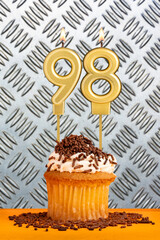 Chocolate cupcake with candle number 98 - Birthday on industrial metallic background.