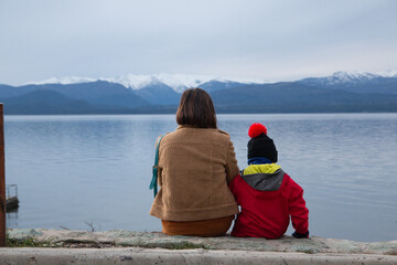 Madre e hijo junto al lago en invierno, contemplando el paisaje