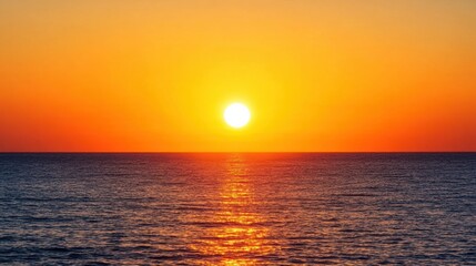 A vibrant orange sunset over the ocean, with the sun dipping just below the horizon.