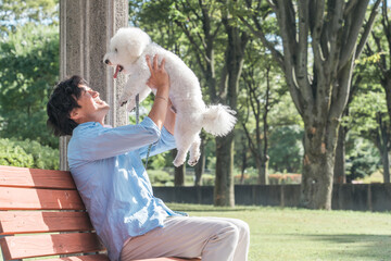 犬の散歩をする愛犬家の中高年男性・ドッグセラピー（抱く・抱っこ）

