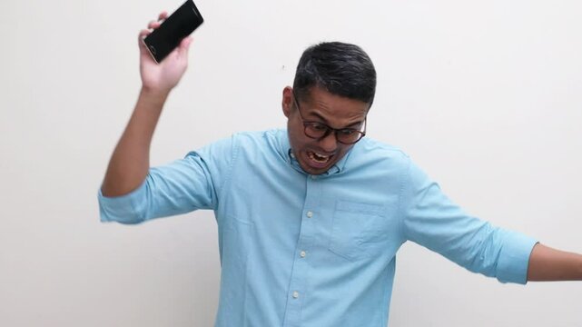 A man showing very angry expression and smashing his phone to the floor