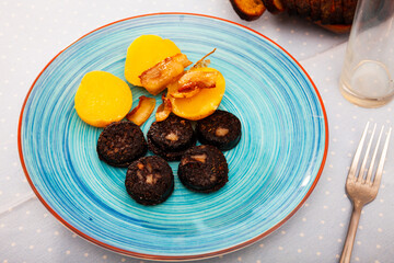 Fried morcilla (blood sausage with rice) served with side dish of baked potatoes