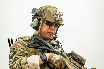 A group of military men in combat gear patrol in the middle of a desert and tropical jungle. Soldiers in full combat gear in dry weather conditions assemble and march on a mission.