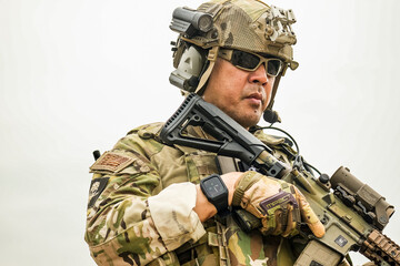 A group of military men in combat gear patrol in the middle of a desert and tropical jungle....