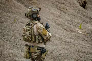 Fototapeta premium A group of military men in combat gear patrol in the middle of a desert and tropical jungle. Soldiers in full combat gear in dry weather conditions assemble and march on a mission.