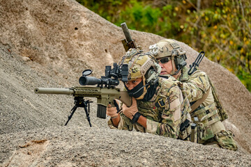 A group of military men in combat gear patrol in the middle of a desert and tropical jungle....