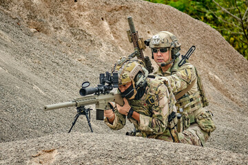 A group of military men in combat gear patrol in the middle of a desert and tropical jungle....