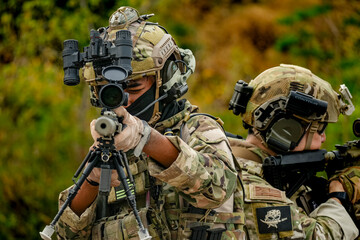 Fototapeta premium A group of military men in combat gear patrol in the middle of a desert and tropical jungle. Soldiers in full combat gear in dry weather conditions assemble and march on a mission.