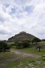 pyramid ruins in archaeological zone located in Queretaro, Mexico. Which is surrounded by nature and vegetation, with a cloudy sky which looks beautiful