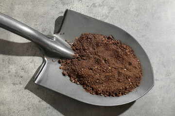 Metal shovel with soil on grey table, top view