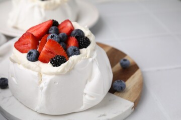 Pavlova cake (meringue dessert) with whipped cream and fresh berries on white table, closeup