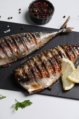 Delicious grilled mackerel, parsley, spices and lemon on white table, above view