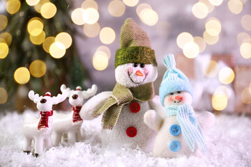 Cute snowmen and deers against blurred Christmas lights, bokeh effect