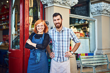 Portrait, man and woman at cafe door with confidence, smile and partnership for small business owner at restaurant. Entrepreneur, team and happy couple at coffee shop entrance with service in Ireland