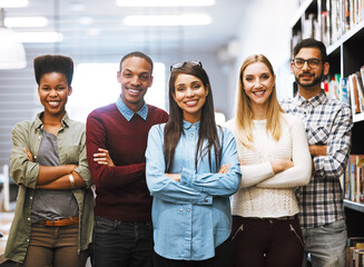 Fototapeta premium Portrait, happy team and students at college library for learning or education by bookshelf. Face, smile and group of people in university for diversity, unity or confident friends with arms crossed