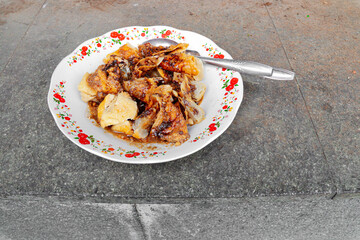 Close-up of Batagor, a traditional Indonesian street food from Bandung, served on a floral-patterned plate with peanut sauce and sweet soy sauce. A spoon rests beside the crispy fried dumplings