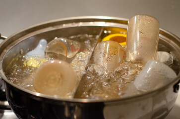 A pot of boiling water with baby bottles and accessories submerged in it. a process of sterilizing baby items.