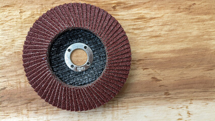 Flap disc. Sandpaper grinding blade on wooden board. Round sandpaper for smoothing wood....