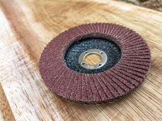 Flap disc. Sandpaper grinding blade on wooden board. Round sandpaper for smoothing wood. Carpenter's tool kit.