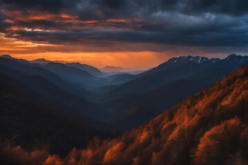 Obraz premium Orange glow of twilight from behind the silhouetted mountain ridge with dramatic blue-grey clouds in the sky
