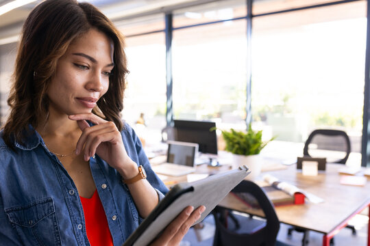 Using tablet, woman reviewing interior design plans in modern office