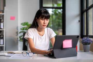 Fototapeta premium Young asian woman using tablet computer working from home
