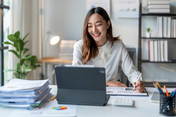 Young asian businesswoman smiling and working on tablet with charts and graphs