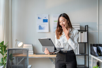 Surprised asian businesswoman looking at digital tablet screen in office