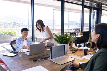 In office, Collaborating on interior design project, diverse team using laptops and discussing plans