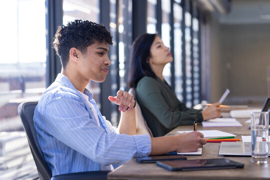 Taking notes and listening attentively, diverse colleagues in modern office meeting