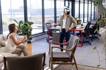 Using VR headset, asian woman discussing interior design with colleague in modern office