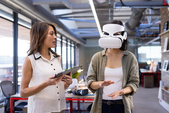 In office, Discussing design ideas, asian woman using VR headset while colleague holds tablet
