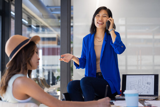 At office, Talking on smartphone, asian woman in blue blazer discussing interior design project