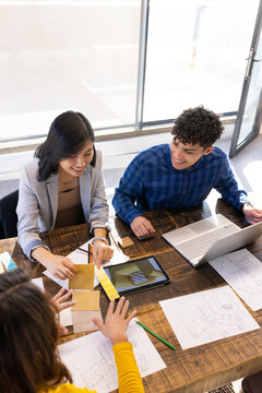 At office, Collaborating on project, diverse team using laptop, tablet, and color swatches