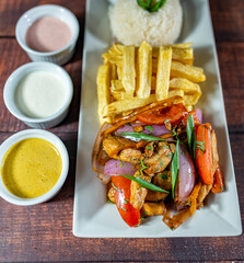 sautéed chicken with french fries and rice, served with homemade creams, peruvian food