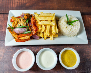sautéed chicken with french fries and rice, served with homemade creams, peruvian food