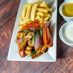 sautéed chicken with french fries and rice, served with homemade creams, peruvian food