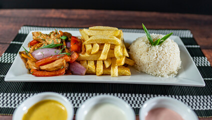 sautéed chicken with french fries and rice, served with homemade creams, peruvian food