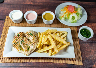 grilled chicken with french fries and fresh salad, accompanied by homemade creams.