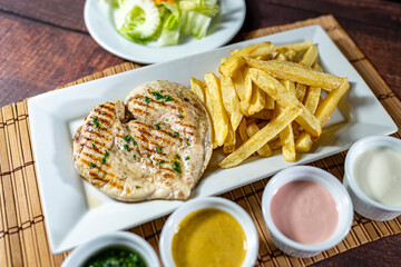 grilled chicken with french fries and fresh salad, accompanied by homemade creams.