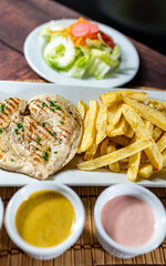 grilled chicken with french fries and fresh salad, accompanied by homemade creams.