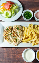 grilled chicken with french fries and fresh salad, accompanied by homemade creams.