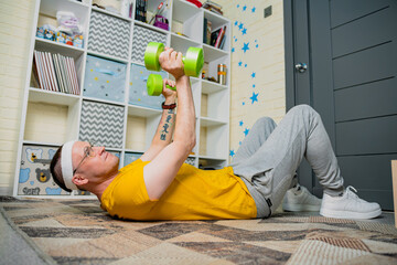 Man performs strength training exercises at home using green dumbbells in a cozy, well-decorated...