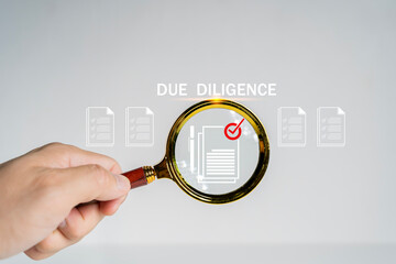 Due diligence concept. Businessman using magnifying glass with due diligence icon on virtual screen...