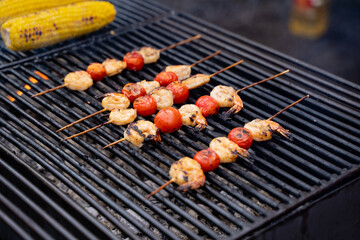 Succulent shrimp and fresh tomatoes are being expertly cooked together on skewers, sizzling away on a hot grill, creating a delicious and appetizing dish that is perfect for any meal