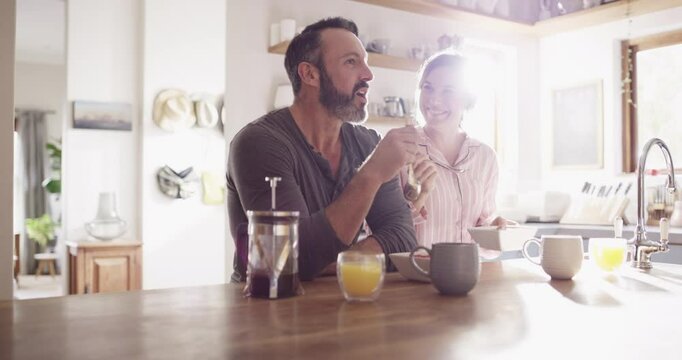 Couple, man or woman and eating breakfast in kitchen for conversation, happy and wellness in home with sunlight. People, meal or feeding on weekend for peace, relax and bonding with love or care